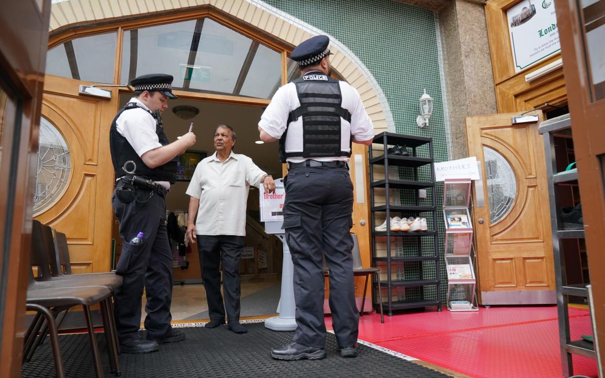 Police officers speak to a staff member at the London Islamic Cultural Society (LICS) and Mosque in Haringey, north London.