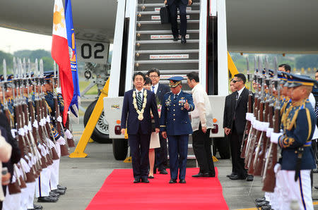 Japanese Prime Minister Shinzo Abe is led the way by a Philippine military official to review honour guards upon arrival for a state visit in metro Manila, Philippines January 12, 2017. REUTERS/Romeo Ranoco