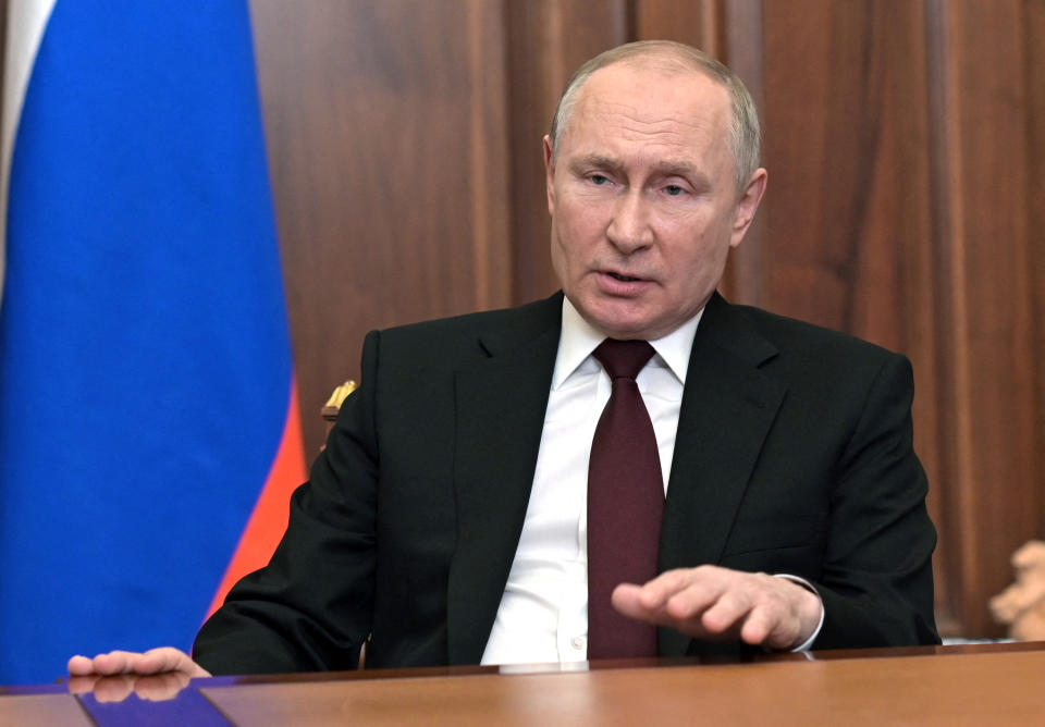 Russian President Vladimir Putin at his desk, with a flag at his side.