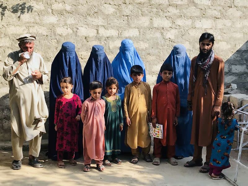 Mohammed Jafar poses for a picture along with widows of his three brothers, their children and his father, in Kunar