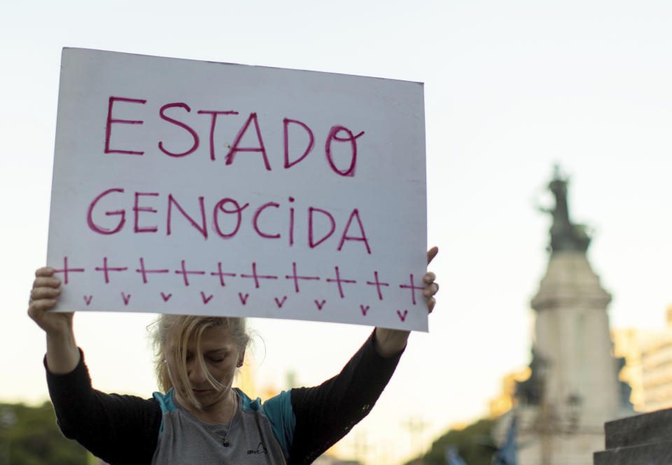 A woman holds a sign that reads in Spanish "Genocidal state" during a march against police brutality, in Buenos Aires, Argentina, Friday, May. 24, 2019. Argentines protested after officers on Monday fired shots that led to the deaths of three teenagers and a young man in a car chase. (AP Photo/Tomas F. Cuesta)