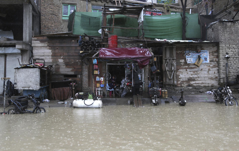 An Afghan shopkeeper waits for customers as heavy rain falls in Kabul, Afghanistan, Tuesday, April 16, 2019. Afghan officials say at least five more people have been killed and 17 are missing as a new wave of heavy rains and flooding swept across the country's western Herat province. (AP Photo/Rahmat Gul)