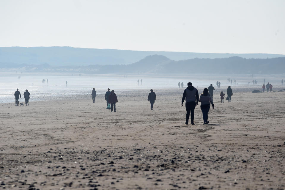 People walk in the sunshine on South Beach, Tenby, Pembrokeshire, Wales, Britain. Photo: Rebecca Naden/Reuters