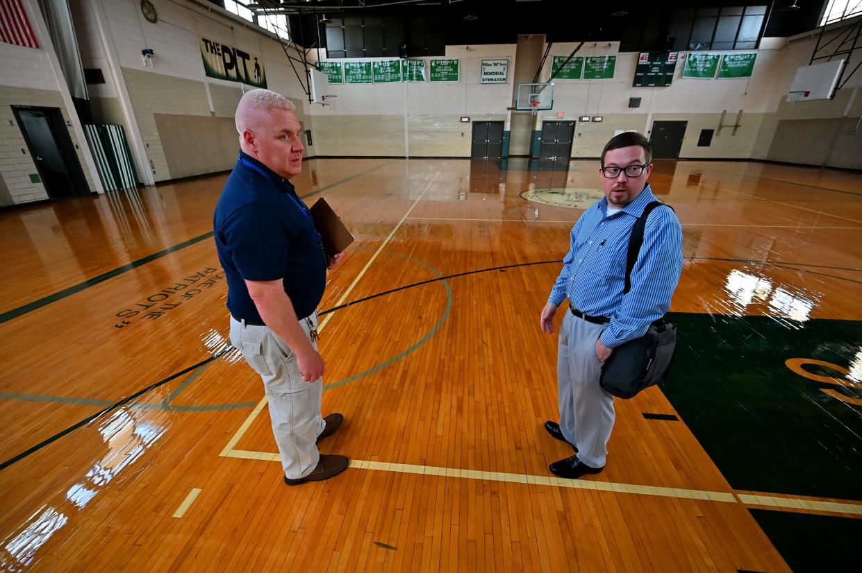 From left, Richard Ikonen, director of facilities, and Ryan Hacker, assistant director, look over the newly refinished floor at Burncoat High School.