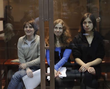 FILE PHOTO: Members of the female punk band "Pussy Riot" (L-R) Yekaterina Samutsevich, Maria Alyokhina and Nadezhda Tolokonnikova sit in a glass-walled cage before a court hearing in Moscow October 10, 2012. REUTERS/Maxim Shemetov