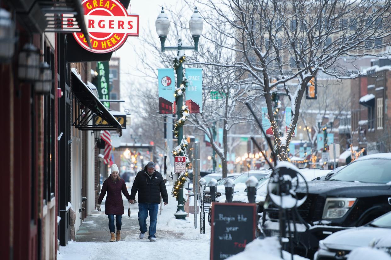 A couple walks on the snowy sidewalk on Wednesday, Jan. 10, 2024 on Phillips Avenue in Downtown Sioux Falls.