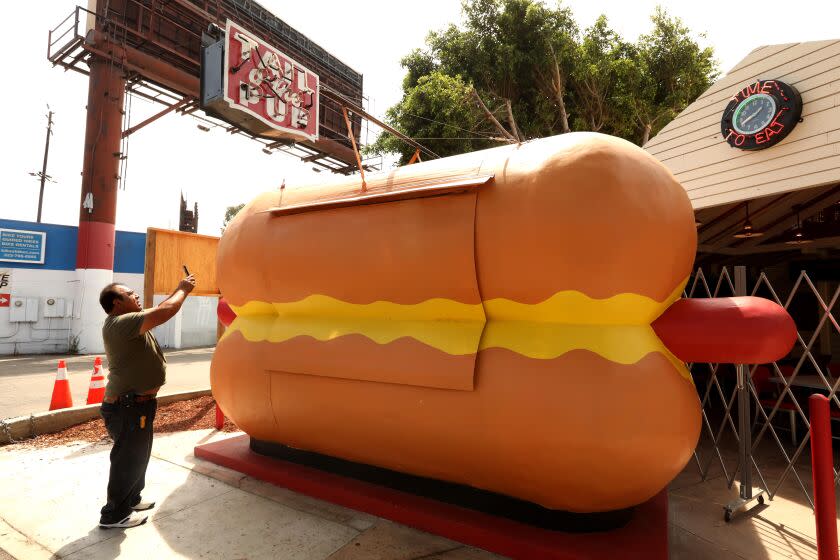 WEST HOLLYWOOD, CA - JULY 20, 2022 - - READY FOR ITS CLOSE-UP - Painter Elio Crestles takes a photo of the restored Tail O' The Pup hours before its grand reopening at 6 p.m. on National Hot Dog Day at its new location at 8512 Santa Monica Boulevard in West Hollywood on July 20, 2022. Crestles repainted the famed hot dog stand along with the attached restaurant. The grand re-opening will have a ribbon cutting ceremony, search lights and attend by Los Angeles digniteries. The preservation-minded 1933 Group restored the historic 76-year-old street stand. (Genaro Molina / Los Angeles Times)