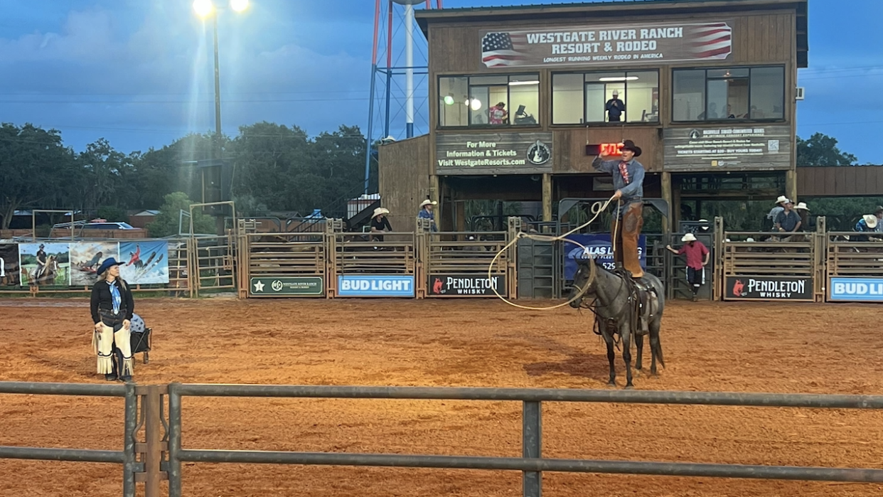 man standing on a horse during a rodeo
