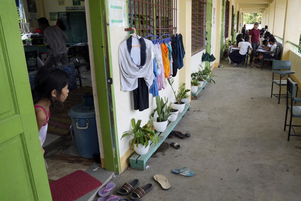 An evacuee looks out of their room as students hold class along the hallways, because the school was converted into a temporary evacuation center, at Malilipot town, Albay province, northeastern Philippines, Thursday, June 15, 2023. Thousands of residents have left the mostly poor farming communities within a 6-kilometer (3.7-mile) radius of Mayon's crater in forced evacuations since volcanic activity spiked last week. (AP Photo/Aaron Favila)