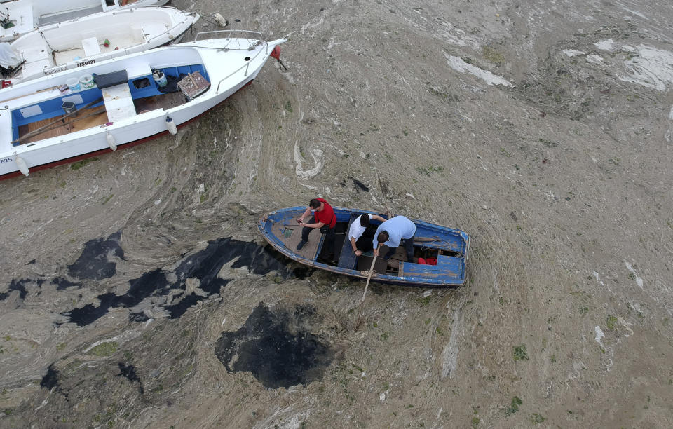 An aerial photo of Pendik port in Asian side of Istanbul, Friday, June 4, 2021, with people and a huge mass of marine mucilage, a thick, slimy substance made up of compounds released by marine organisms, in Turkey's Marmara Sea. Turkey's President Recep Tayyip Erdogan promised Saturday to rescue the Marmara Sea from an outbreak of "sea snot" that is alarming marine biologists and environmentalists. Erdogan said untreated waste dumped into the Marmara Sea and climate change had caused the sea snot bloom. Istanbul, Turkey's largest city with some 16 million residents, factories and industrial hubs, borders the sea.(AP Photo)