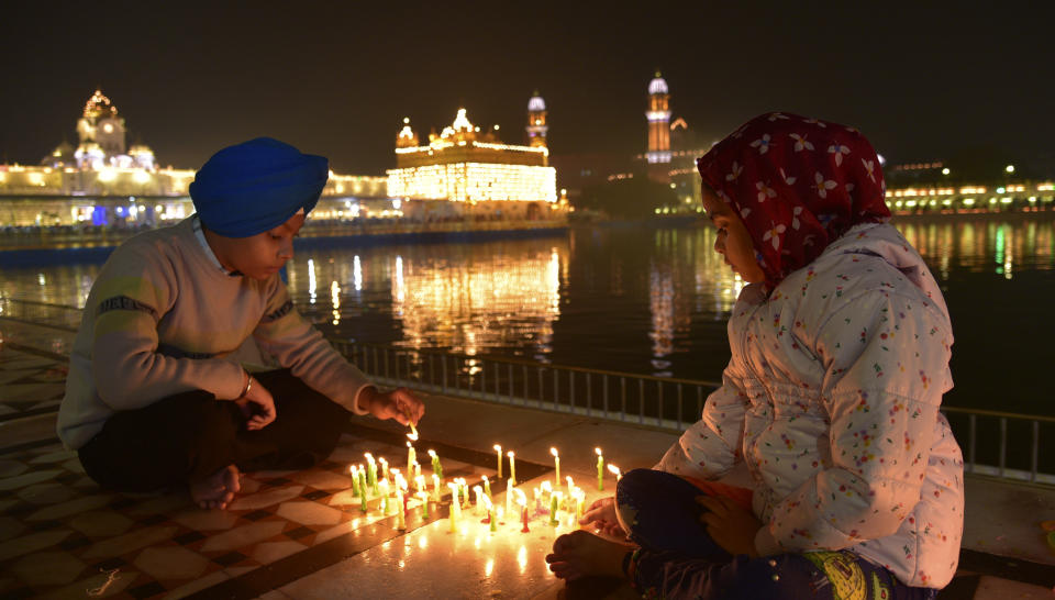 Young Sikhs light candles at the illuminated Golden Temple, Sikhs holiest shrine, early morning to mark the birth anniversary of Guru Nanak, the first Sikh Guru and the founder of Sikhism, in Amritsar, India, Monday, Nov. 27, 2023. (AP Photo/Prabhjot Gill)