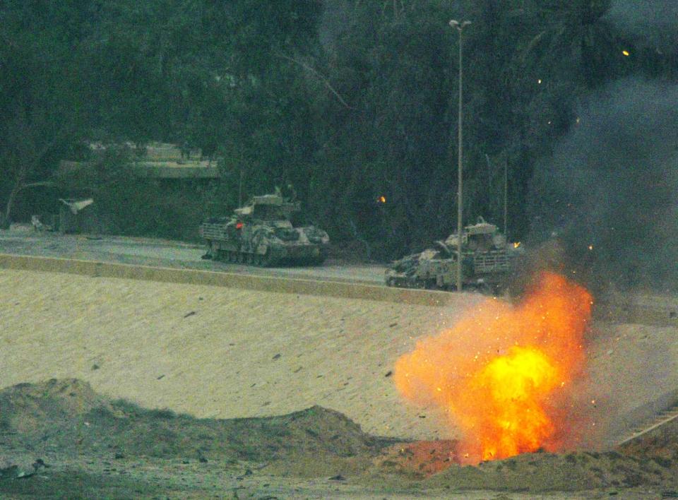 Bradley amored vehicles clear Iraqi Republican Guard bunkers on the road around Baghdad's main presidential palace compound April 7, 2003. (PATRICK BAZ/AFP via Getty Images)