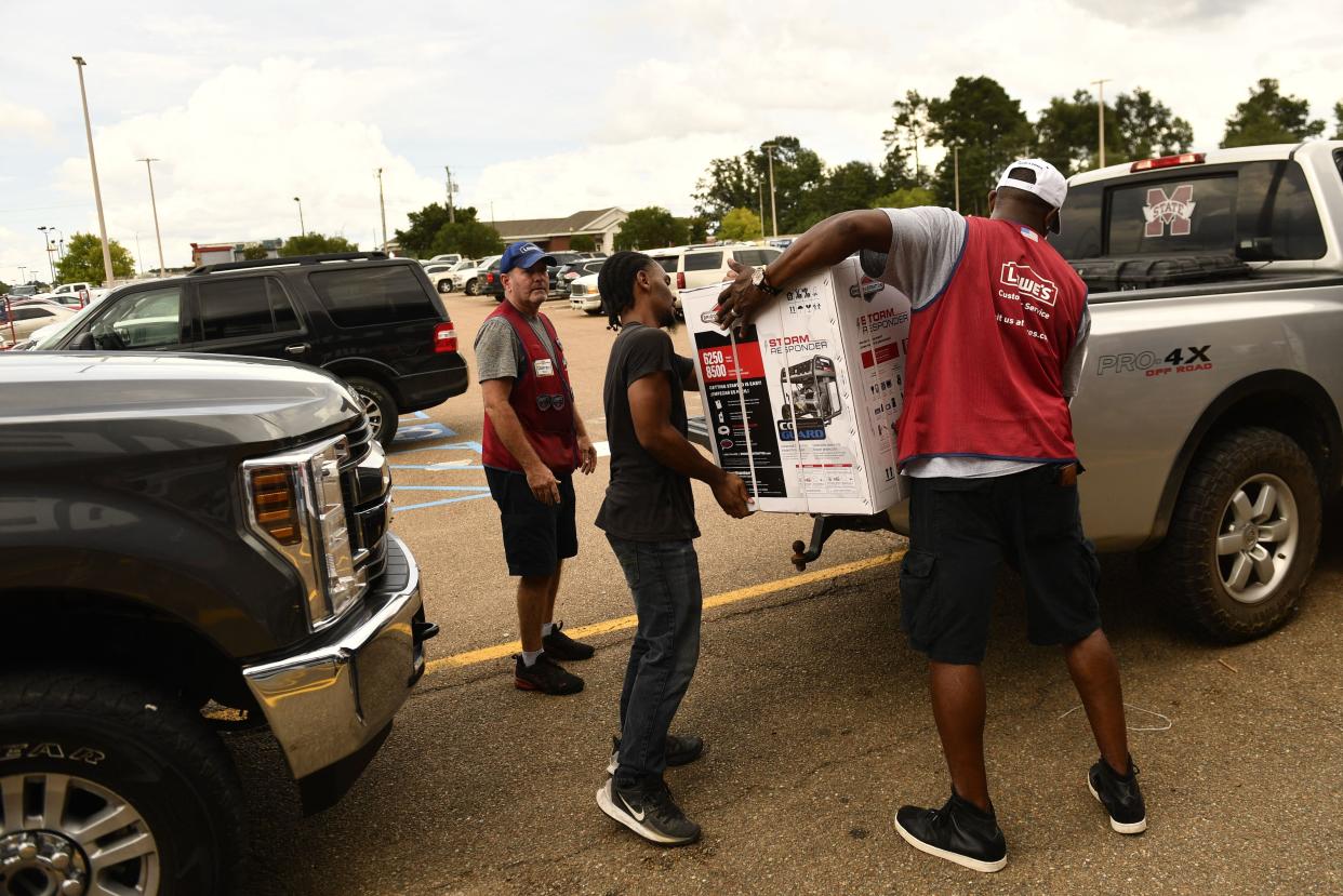 Lowes employees help a customer load a generator onto a pickup truck in McComb, Miss. as residents prepare for Hurricane Ida on Aug. 28, 2021.