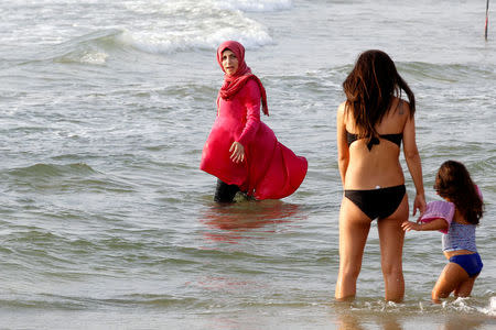 A Muslim woman wearing a Hijab stands in the Mediterranean Sea as an Israeli woman wearing a bikini stands nearby at a beach in Tel Aviv, Israel August 30, 2016. Picture taken August 30, 2016. REUTERS/Baz Ratner