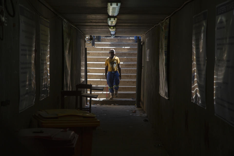 A miner walks at the entrance of a goldmine shaft in Springs, South Africa, Tuesday, Oct. 24, 2023. A group of miners from an unregistered, rival union are holding around 500 of their colleagues underground for the second day at the mine over a union dispute. Some 15 miners have been injured in scuffles, the head of the mine said on Tuesday. (AP Photo/Denis Farrell)