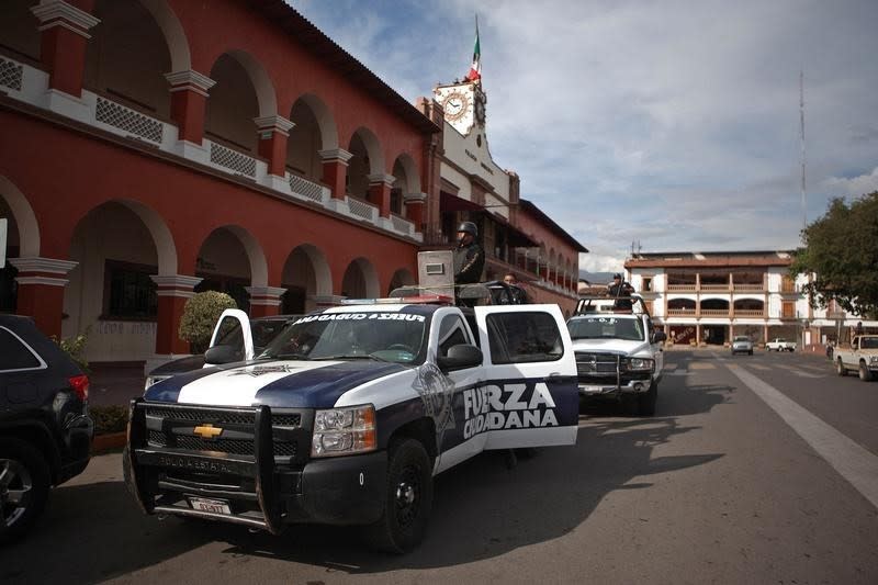 Police stand guard outside the town hall after a shooting between federal forces and armed civilians in the town of Apatzingan, Michoacan January 6, 2015.  REUTERS/Alan Ortega 