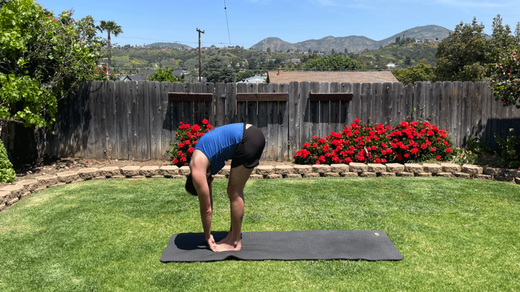 Man standing on a yoga mat outside in his back yard s