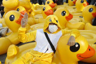 A protester flashes the three-finger protest gesture while wearing an outfit of a yellow duck, which has become a good-humored symbol of resistance during anti-government rallies, Wednesday, Nov. 25, 2020, in Bangkok, Thailand. Thai authorities have escalated their legal battle against the students leading pro-democracy protests, charging 12 of them with violating a harsh law against defaming the monarchy. (AP Photo/Sakchai Lalit)