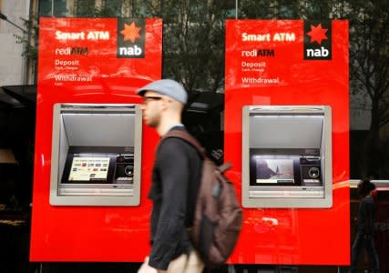 A man walks past ATM machines at a National Australia Bank branch in Sydney, Australia April 20, 2018. REUTERS/Edgar Su