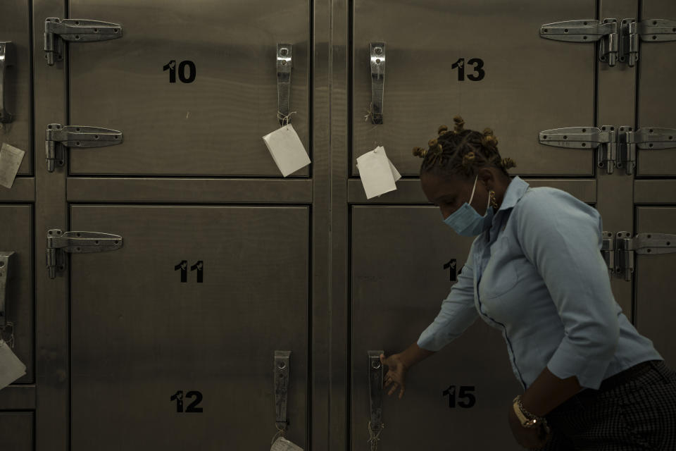 This image provided by World Press Photo is part of a multimedia project by Associated Press' Renata Brito and Felipe Dana titled Adrift, won the World Press Photo Africa Regional Winner Open Format category and shows a mortuary technician opening the door of a refrigerator used to store the remains of migrants recovered from inside the Mauritania boat that appeared drifting near the island of Tobago, in Scarborough, Trinidad and Tobago, Tuesday, Jan. 25, 2022. In May 2021 a boat from Mauritania full of dead men was found off the coast of the Caribbean Island of Tobago. Who were these men and why were they on the other side of the Atlantic Ocean? Two visual journalists sought answers, uncovering a story about migrants from West Africa who seek opportunity in Europe via an increasingly popular but treacherous Atlantic route. (AP Photo/Felipe Dana)