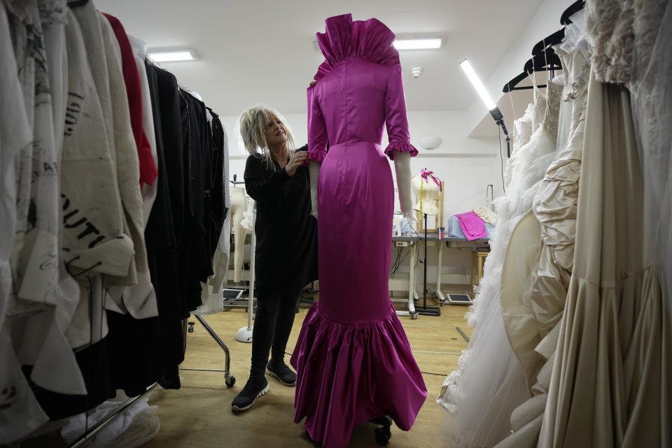 British designer Elizabeth Emanuel stands beside a replica of an evening gown she designed for the then Lady Diana Spencer to wear at a Buckingham Palace party a few days before her marriage to Prince Charles in 1981, in London, Friday, Nov. 18, 2022. Emanuel recreated the dress for her own archive and to show another side of Diana, who Emanuel believes has been misrepresented by "The Crown," the popular Netflix series that has brought the story of the princess and her ill-fated marriage to a new generation. (AP Photo/Kin Cheung)