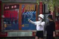 People wearing face masks to protect against the new coronavirus take photos near billboards honoring medical workers who responded to the coronavirus outbreak in Wuhan at a public park in Beijing, Friday, June 26, 2020. China reported a further decline in new cases Friday with about a dozen mostly in Beijing, where mass testing has been done following an outbreak that appears to have been largely brought under control. (AP Photo/Mark Schiefelbein)