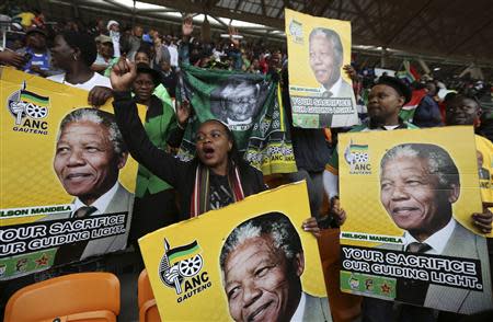 People hold placards of former South African President Nelson Mandela at the First National Bank (FNB) Stadium, also known as Soccer City, during the national memorial service for Mandela in Johannesburg December 10, 2013. REUTERS/Siphiwe Sibeko