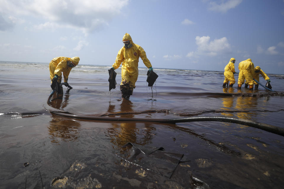 Workers carry out a clean-up operation on Mae Ramphueng Beach after a pipeline oil spill off the coast of Rayong province in eastern Thailand, Saturday, Jan. 29, 2022, At least 20 tons of oil leaked Tuesday night from an undersea hose at an offshore mooring point of the Star Petroleum Refining Co. used to load tankers, and despite efforts to disperse or contain it, some reached the beach Saturday morning, while a large slick remains at sea. (AP Photo/Nava Sangthong)