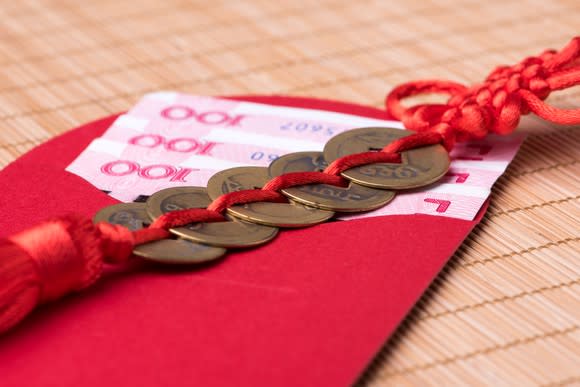 Chinese coins on top of a red envelope containing Chinese money.