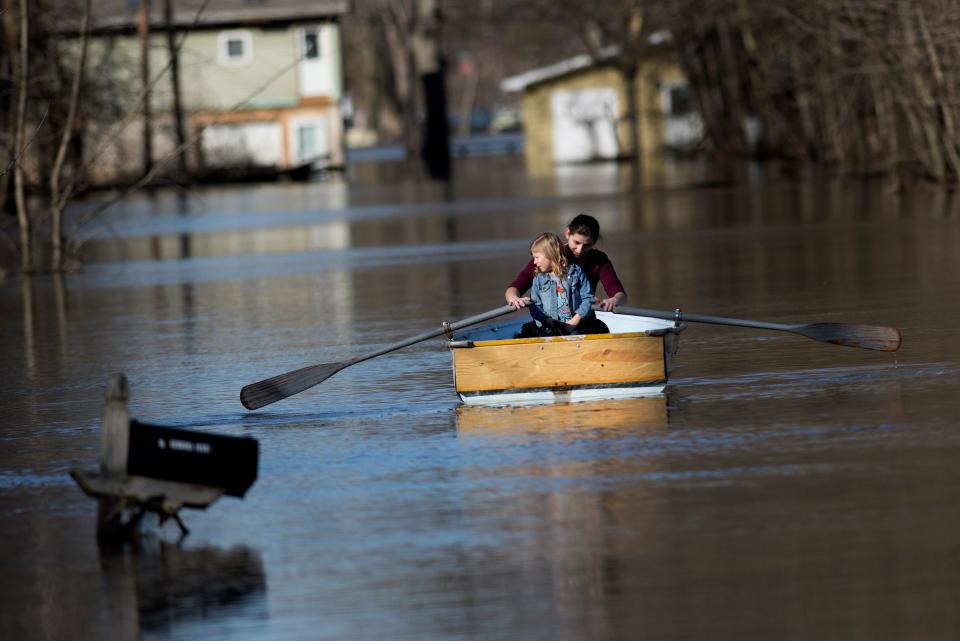 <p>Emily Snyder teachers her daughter, Skyler, 4, how to row the boat as they check out their home on Forrest Ridge Avenue NE in Plainfield Township, Mich., on Monday, Feb. 26, 2018. River levels are dropping in Michigan after flooding last week and over the weekend because of heavy rains and melting snow. The National Weather Service says the Grand River in Grand Rapids crested Sunday above 20 feet (6 meters), more than 2 feet (0.7 meters) higher than flood stage, after peaking Friday in the Lansing area. Still, local states of emergency were in effect Monday along portions of the river. (Photo: Neil Blake/The Grand Rapids Press via AP) </p>