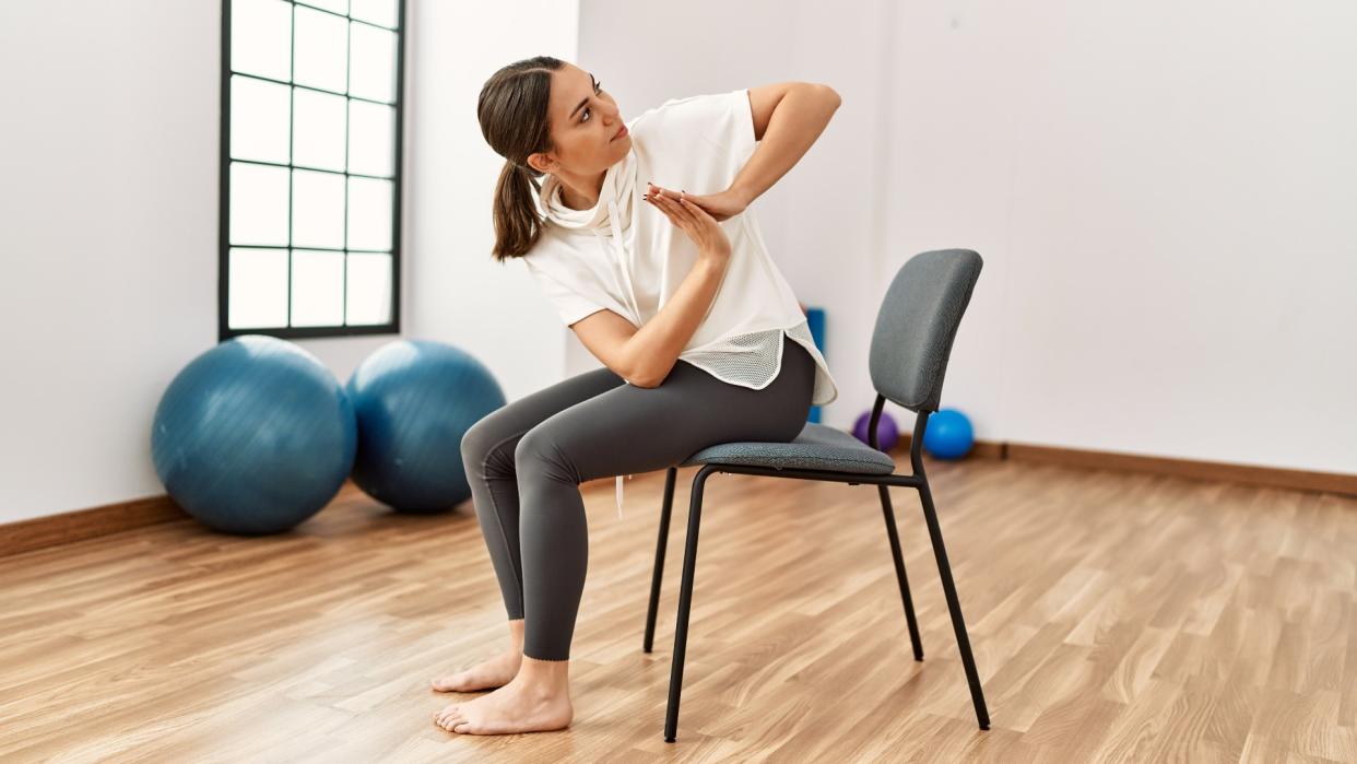  Woman performing a yoga exercise during seated chair yoga routine in an exercise studio 