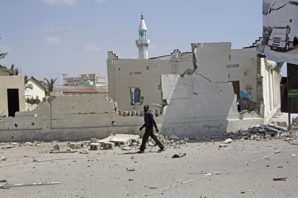 A man walks past destroyed buildings after a large blast in the capital city of Mogadishu, Somalia, Saturday, Dec. 22, 2018. Police say a suicide car bomb exploded near the presidential palace killing and injuring a number of people. (AP Photo/Farah Abdi Warsameh)