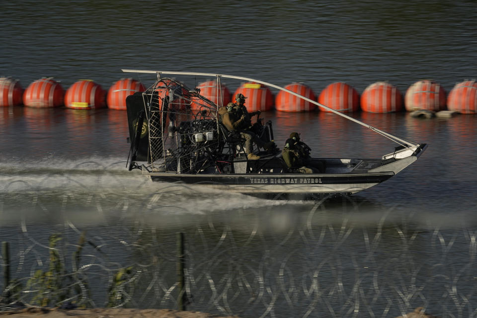 A Texas Highway Patrol boat passes a chain of buoys deployed to help curb illegal crossings along the Rio Grande, Thursday, Oct. 19, 2023, in Eagle Pass, Texas. Starting in March, Texas will give police even broader power to arrest migrants while also allowing local judges to order them out of the U.S. under a new law signed by Republican Gov. Greg Abbott. (AP Photo/Eric Gay)