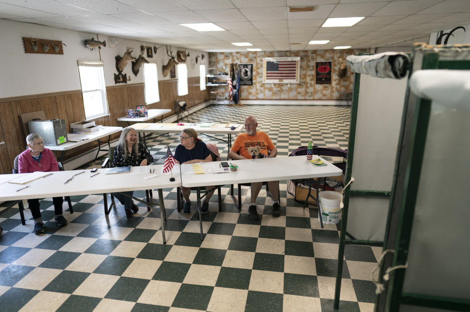 FILE - Polling place workers from left, Ferne Ramsey, Fay Somers, Donna Appleby holding her her dog Daisy Mae, and Jeffery Appleby, wait for voters during the Pennsylvania primary election at the LSL Sportsman's club in Orrstown, Pa., May 17, 2022. Voting could feel different in this year's midterms, as the election falsehoods told by former President Donald Trump and many of his supporters have created a ripple effect across the country. (AP Photo/Carolyn Kaster, File)