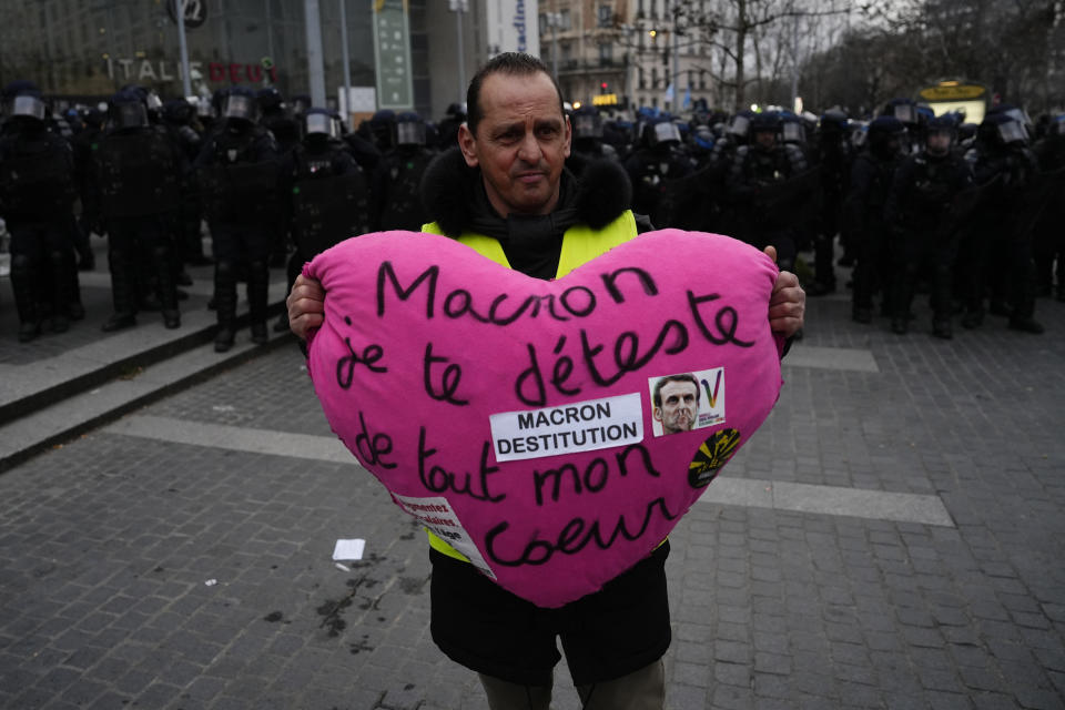 A demonstrator holds a heart reading "Macron I hate you from all my heart" during a demonstration, Tuesday, March 7, 2023 in Paris. Demonstrators were marching across France on Tuesday in a new round of protests and strikes against the government's plan to raise the retirement age to 64, in what unions hope to be their biggest show of force against the proposal. (AP Photo/Lewis Joly)