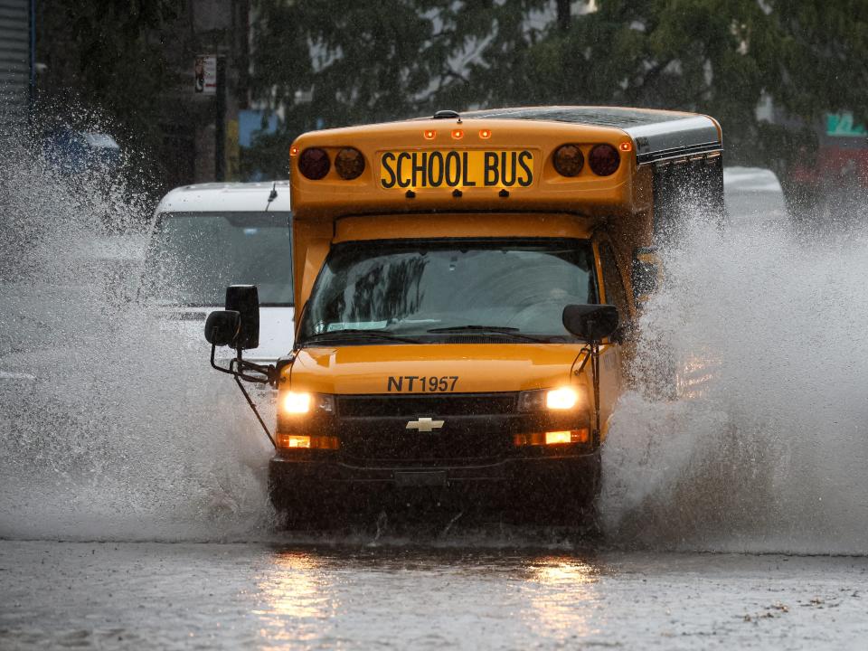 A school bus drives through a flooded road in New York City.