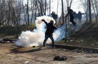 A migrant throws a tear gas canister back during clashes with Greek police, at the Turkey's Pazarkule border crossing with Greece's Kastanies, in Edirne