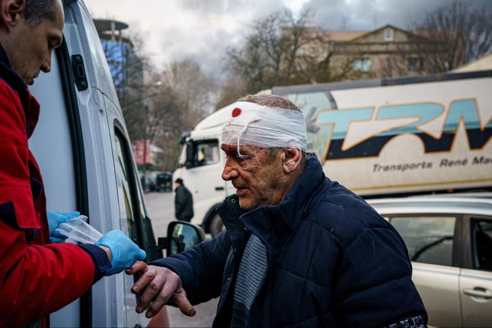 Спасатель помогает пострадавшему после российской бомбардировки украинского города Херсон (AFP через Getty Images)