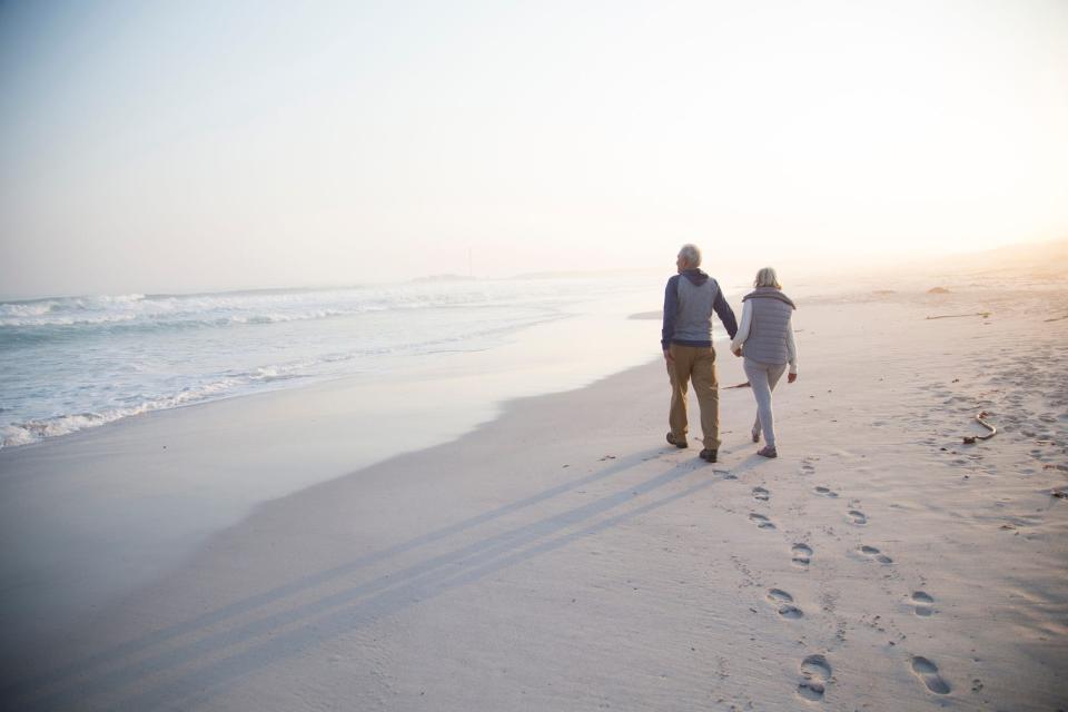 An older couple walking along the beach.