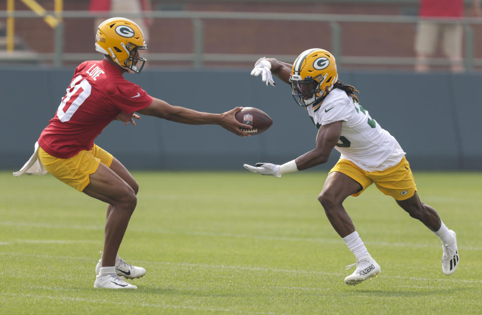 Green Bay Packers' quarterback Jordan Love (10) hands the ball off to Green Bay Packers' running back Aaron Jones (33) during NFL football training camp Saturday, July 31, 2021, in Green Bay, Wis. (AP Photo/Matt Ludtke)