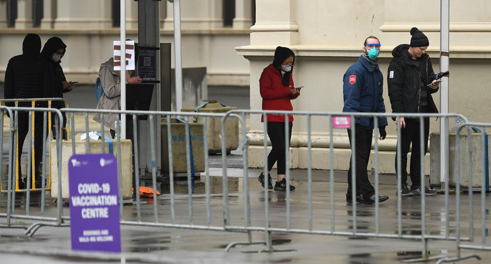 People are seen waiting in a line outside the vaccination centre at the Royal Exhibition Building in Melbourne. Source: AAP