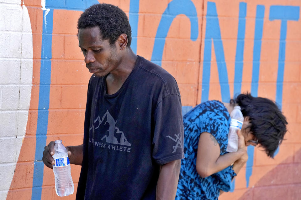 Homeless people try to cool down with chilled water outside the Justa Center, a day center for homeless people 55 years and older, Friday, July 14, 2023 in downtown Phoenix. Phoenix hit 112 degrees on Friday, marking the city's 15th consecutive day of 110 degree-plus temperatures and putting it on track to beat the longest measured stretch of such heat. The record is 18 days, recorded in 1974. Desert residents accustomed to scorching summers are feeling the grip of the heat wave hitting the Southwest this week.(AP Photo/Matt York)