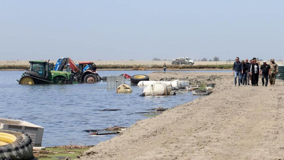 California Gov. Gavin Newsom, far left, looks at farm machinery that is flooded as he walks on a levee at Hansen Ranches on 6th Avenue Tuesday, April 25, 2023, south of Corcoran, CA. María G. Ortiz-Briones/mortizbriones@vidaenelvalle.com