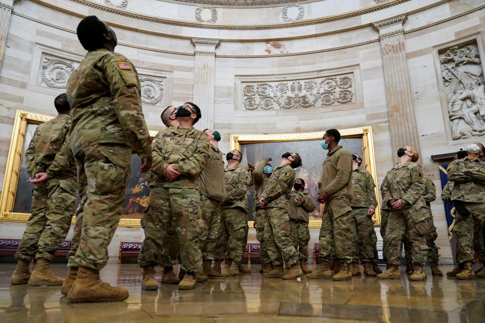 National Guard members crane their necks to look at the ceiling of the Capitol