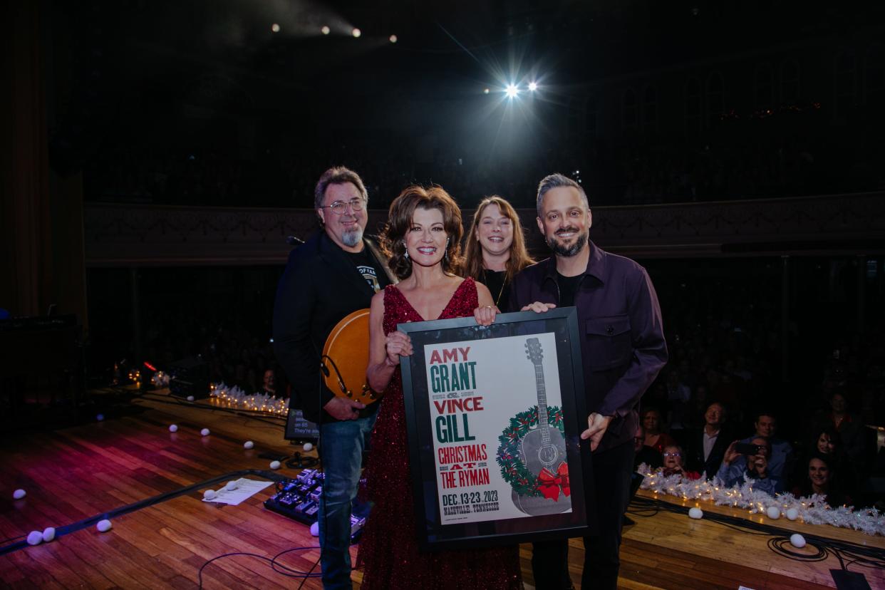 Vince Gill, Amy Grant, Chrissy Hall, Director of Concerts for Ryman Auditorium, Nate Bargatze and a Hatch Show Print commemorating Gill and Grant's 100th Christmas performance at the Ryman Auditorium