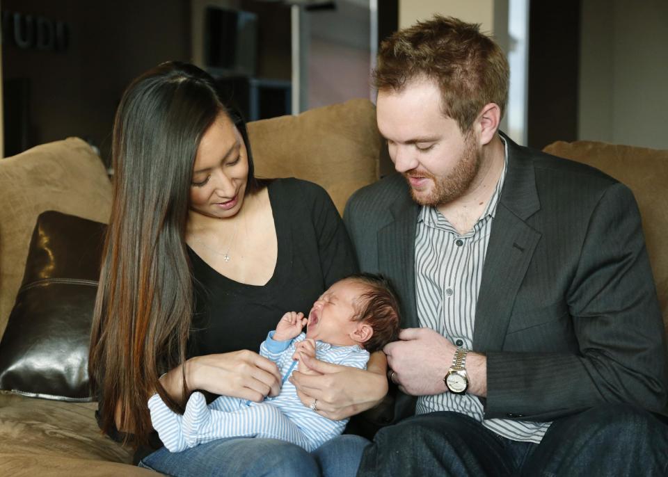 Jennifer Rogers, left, and Nyle Rogers, right, look at their son, Jack Nicolas Rogers, in their home in Edmond, Okla., Tuesday, Jan. 14, 2014. Jack Nicolas Rogers was born Dec. 21, 2013. Jennifer Rogers is formerly Jennifer Doan, a Plaza Towers schoolteacher who was the subject of what became an iconic photograph of the Moore, Okla. tornado as firefighters are shown freeing a debris-covered Doan from the rubble of a collapsed wall. Doan was pregnant with Jack Nicolas at the time. Jack's middle name, Nicolas, is in memory of one of her students, who died in the tornado. (AP Photo/Sue Ogrocki)