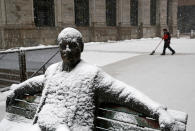 <p>Snow sticks to a statue of a man sitting on a park bench as a worker shovels a light snowfall Wednesday, March 21, 2018, in Baltimore. A spring nor’easter targeted the Northeast on Wednesday with strong winds and a foot or more of snow expected in some parts of the region. (Photo: Patrick Semansky/AP) </p>