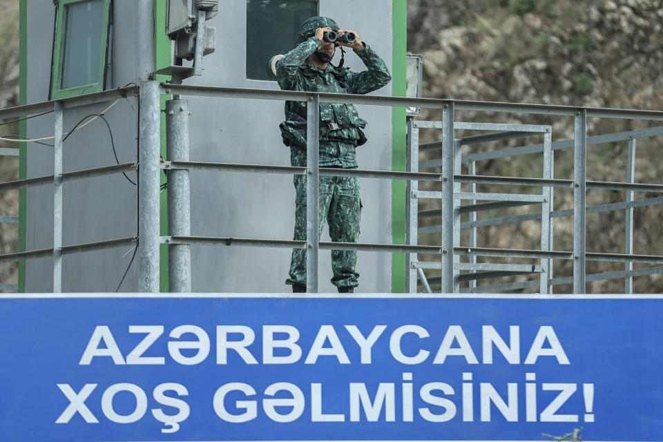 An Azerbaijani serviceman looks through a binocular as he guards the Lachin checkpoint on the in Azerbaijan, Sunday, Oct. 1, 2023. Astsetrayn was one of the last residents of Nagorno-Karabakh to drive out of the region in his own vehicle as part of a grueling weeklong exodus of over 100,000 people — more than 80% of the residents — after Azerbaijan reclaimed the area in a lightning military operation. (AP Photo/Aziz Karimov)