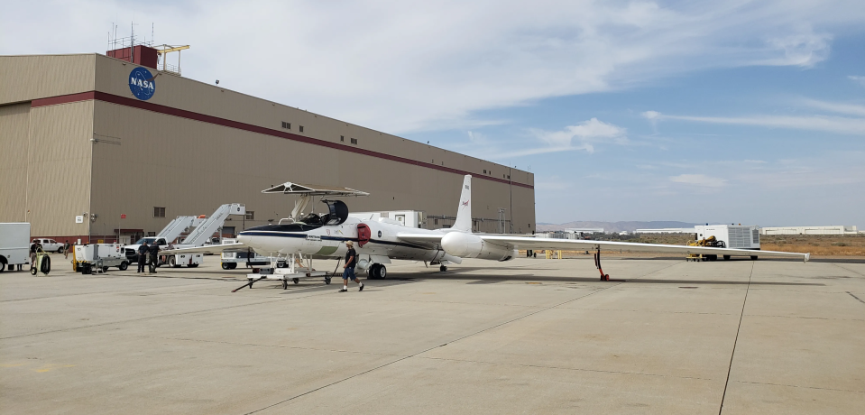 a large white aircraft sits on a tarmac in the desert