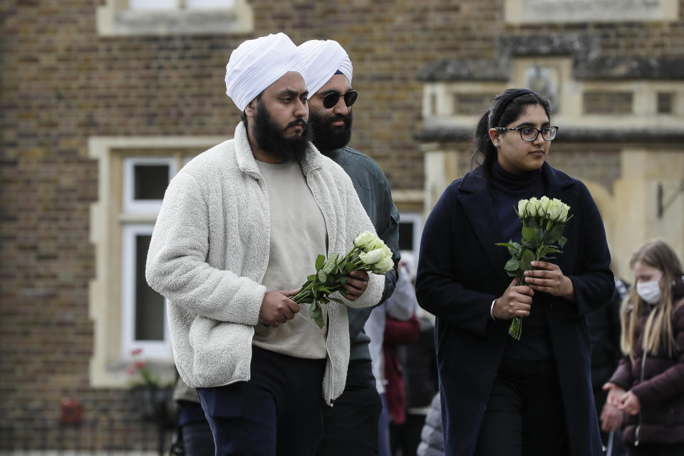 Members of the public bring flowers to Windsor Castle in Windsor, England after the announcement regarding the death of Britain's Prince Philip, Friday, April 9, 2021. Buckingham Palace officials say Prince Philip, the husband of Queen Elizabeth II, has died. He was 99. Philip spent a month in hospital earlier this year before being released on March 16 to return to Windsor Castle. (AP Photo/Kirsty Wigglesworth)